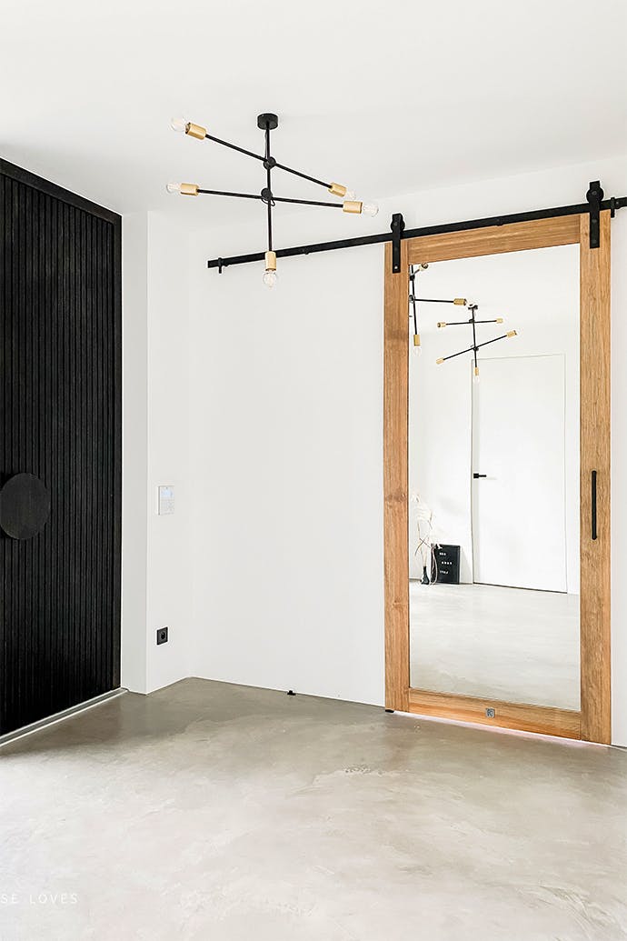 Une chambre blanche avec un sol en microciment et un lustre industriel