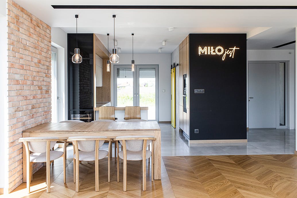 grande table en bois avec chaises dans une salle à manger ouverte reliée à une cuisine moderne