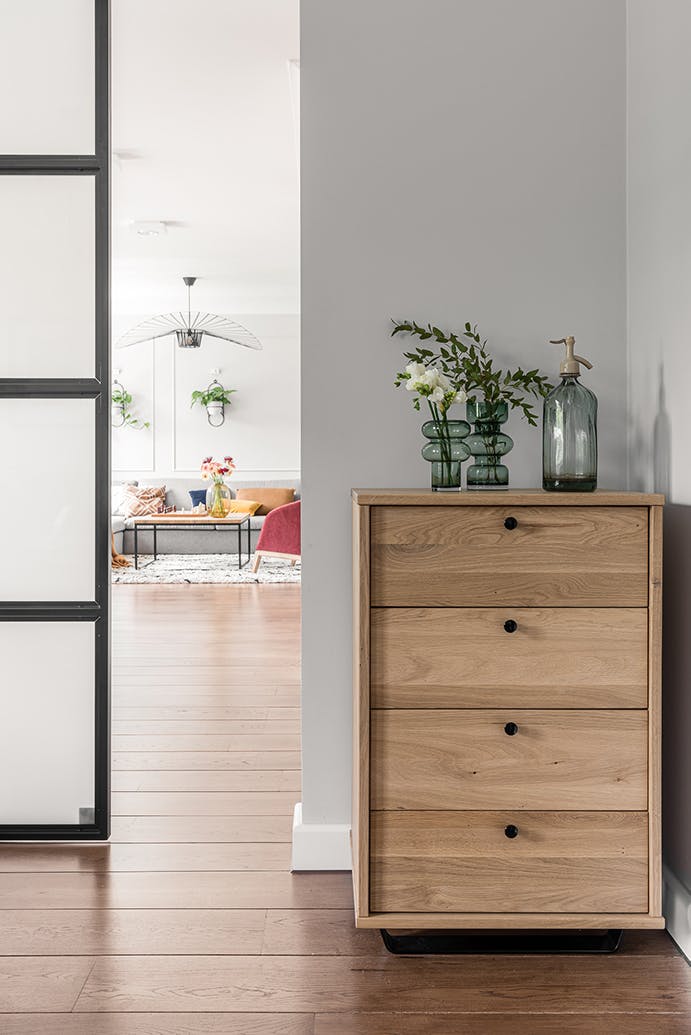 Vases décoratifs en verre vert sur une petite commode en bois clair