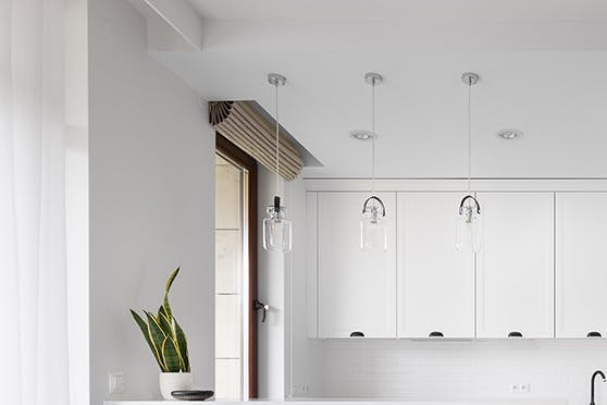Cuisine ouverte décorée en blanc avec des accessoires en métal noir, séparée du salon par un bar à petit déjeuner fini en bleu