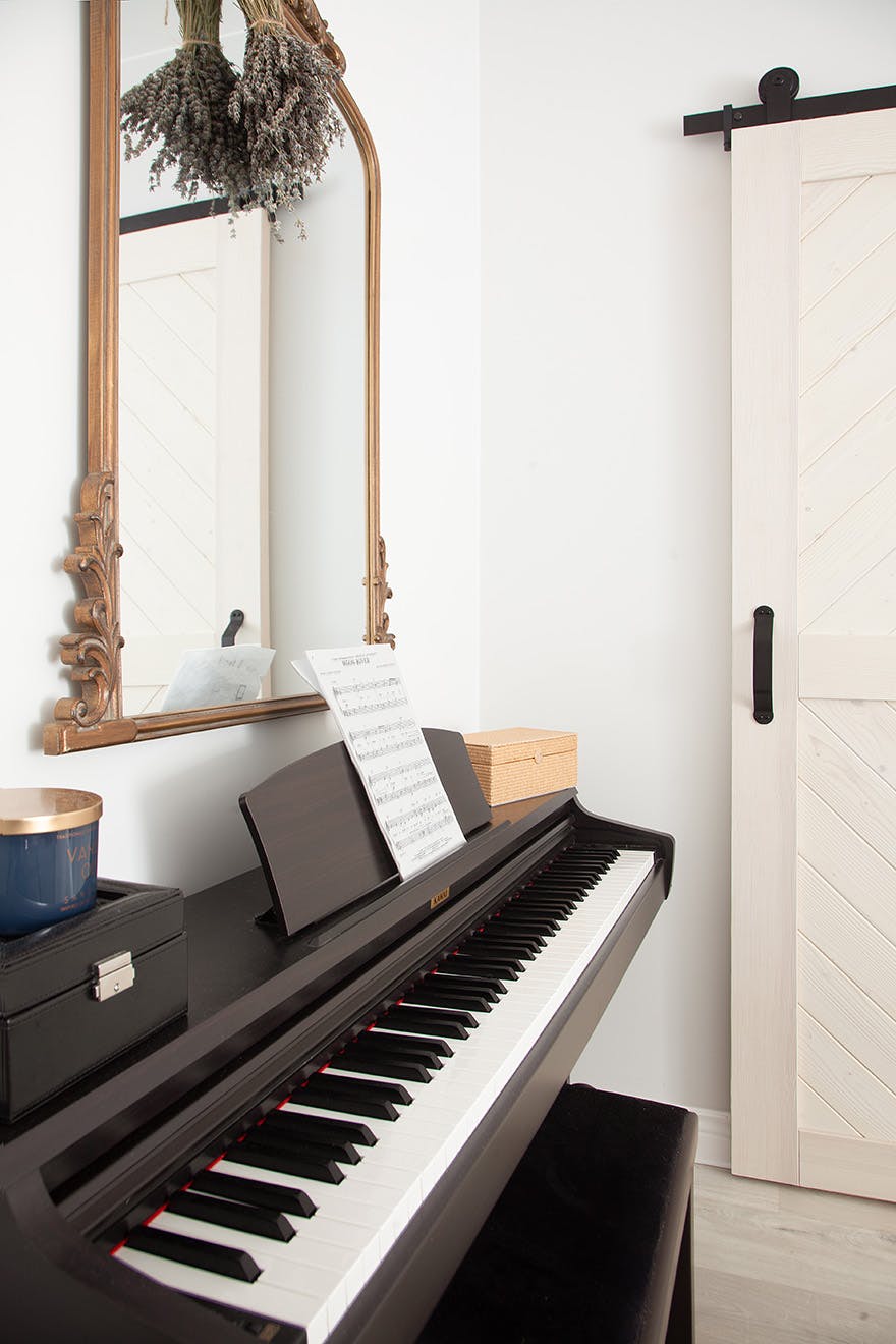 decorative mirror in a wooden frame on the wall above the black piano