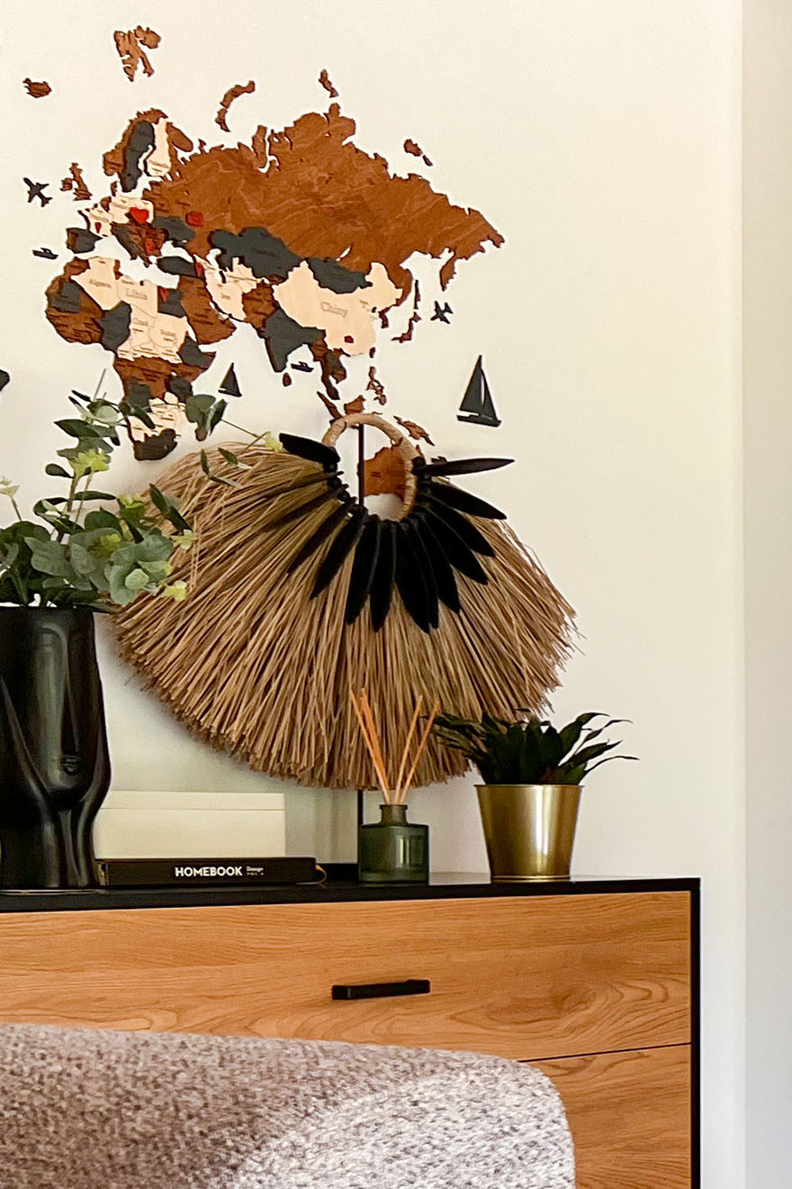 eine hölzerne Weltkarte an der Wand und ein dekorativer Fächer auf der Kommode