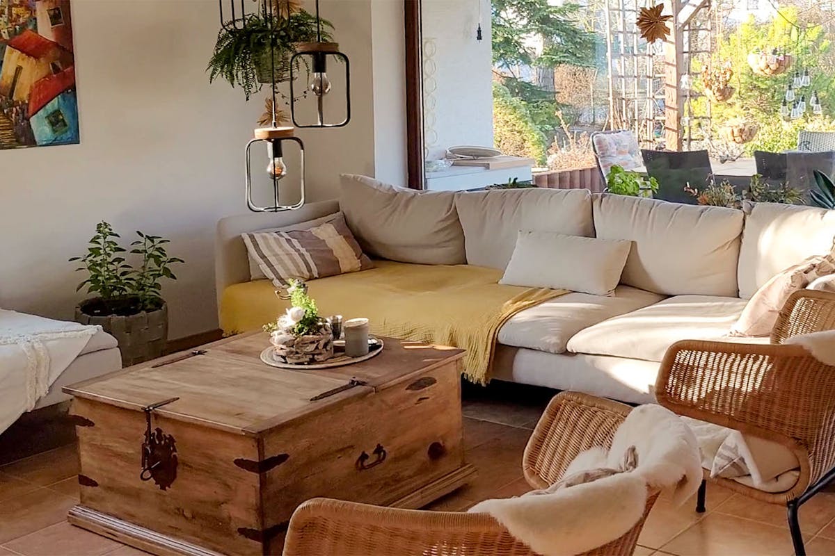 kremowa sofa, stolik ze skrzyni i rattanowe krzesła w salonie