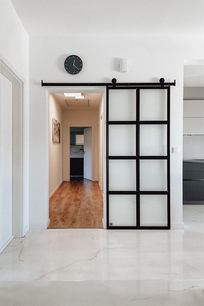 Portes coulissantes en verre dans un cadre en métal noir fermant le couloir