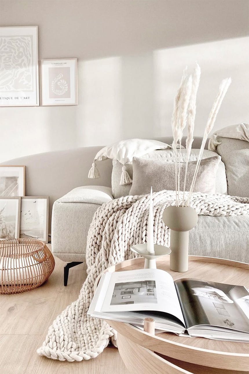 Wohnzimmer in hellen Beigetönen, Wohnzimmer im nordischen Stil, Dekorationen auf dem Couchtisch im Wohnzimmer, beiges Sofa neben einer hellen Wand