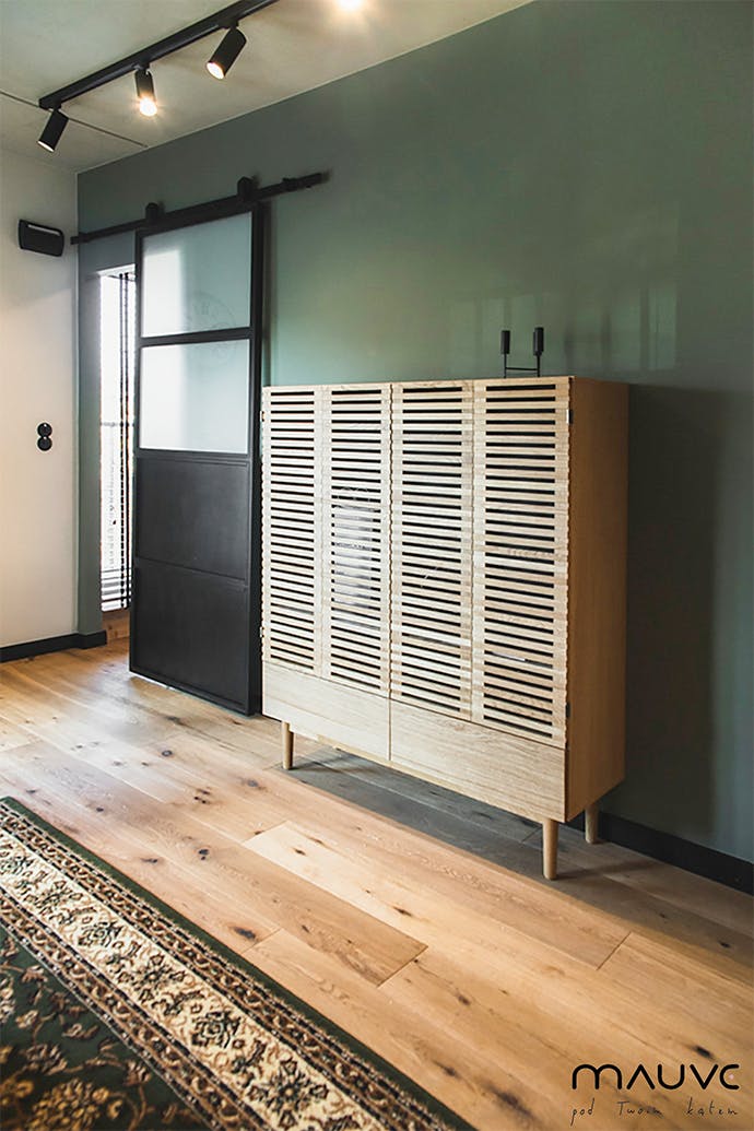 Une commode vintage à côté d'une porte coulissante en métal et verre