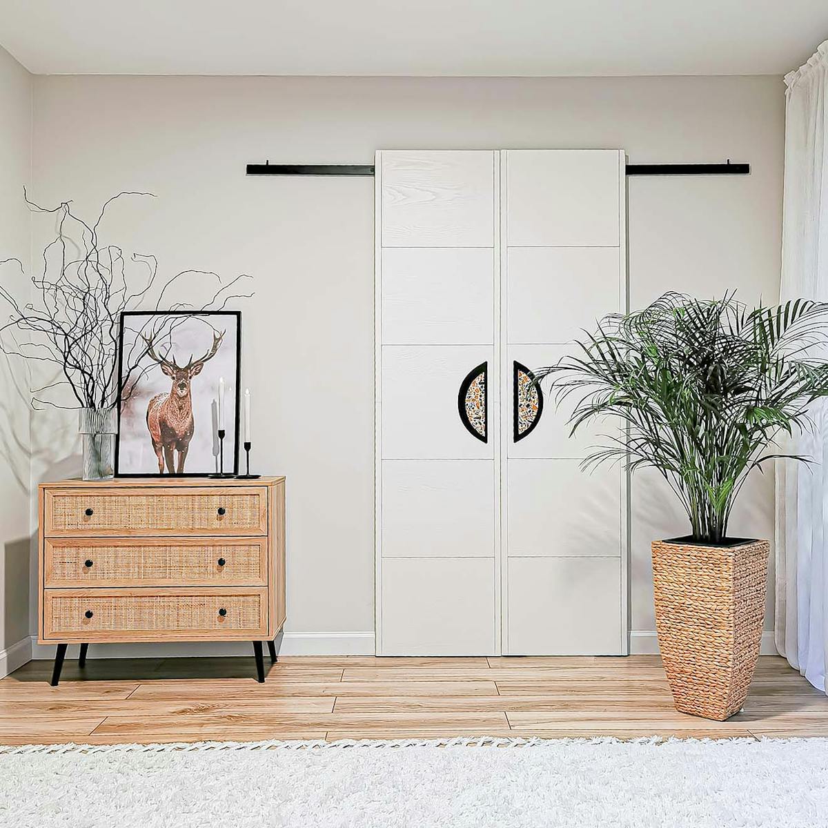 komoda z rattanowymi frontami szuflad stojąca obok podwójnych białych drzwi przesuwnych w stylu minimalistycznym