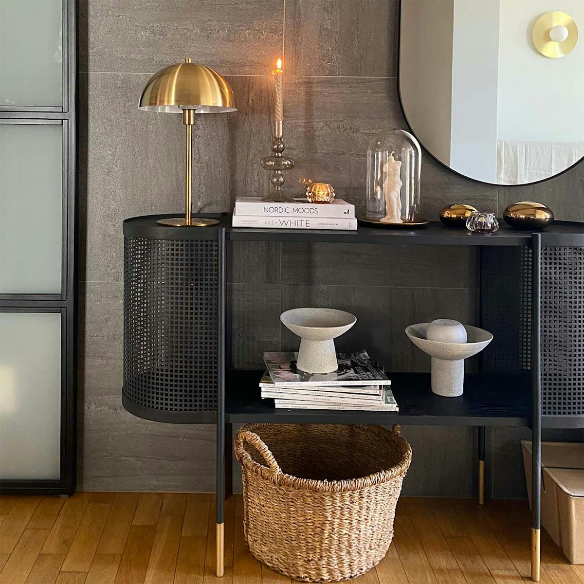Schwarze durchbrochene Konsole in der Halle, Graphitfliesen an der Wand, goldene Lampe auf der schwarzen Konsole, minimalistische Dekorationen auf der Konsole