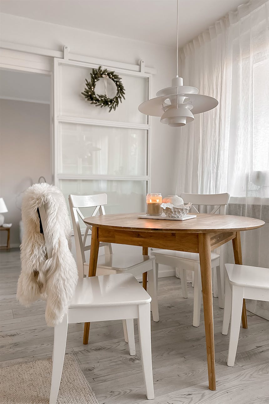 białe krzesła ustawione wokół okrągłego drewnianego stołu w salonie w bloku