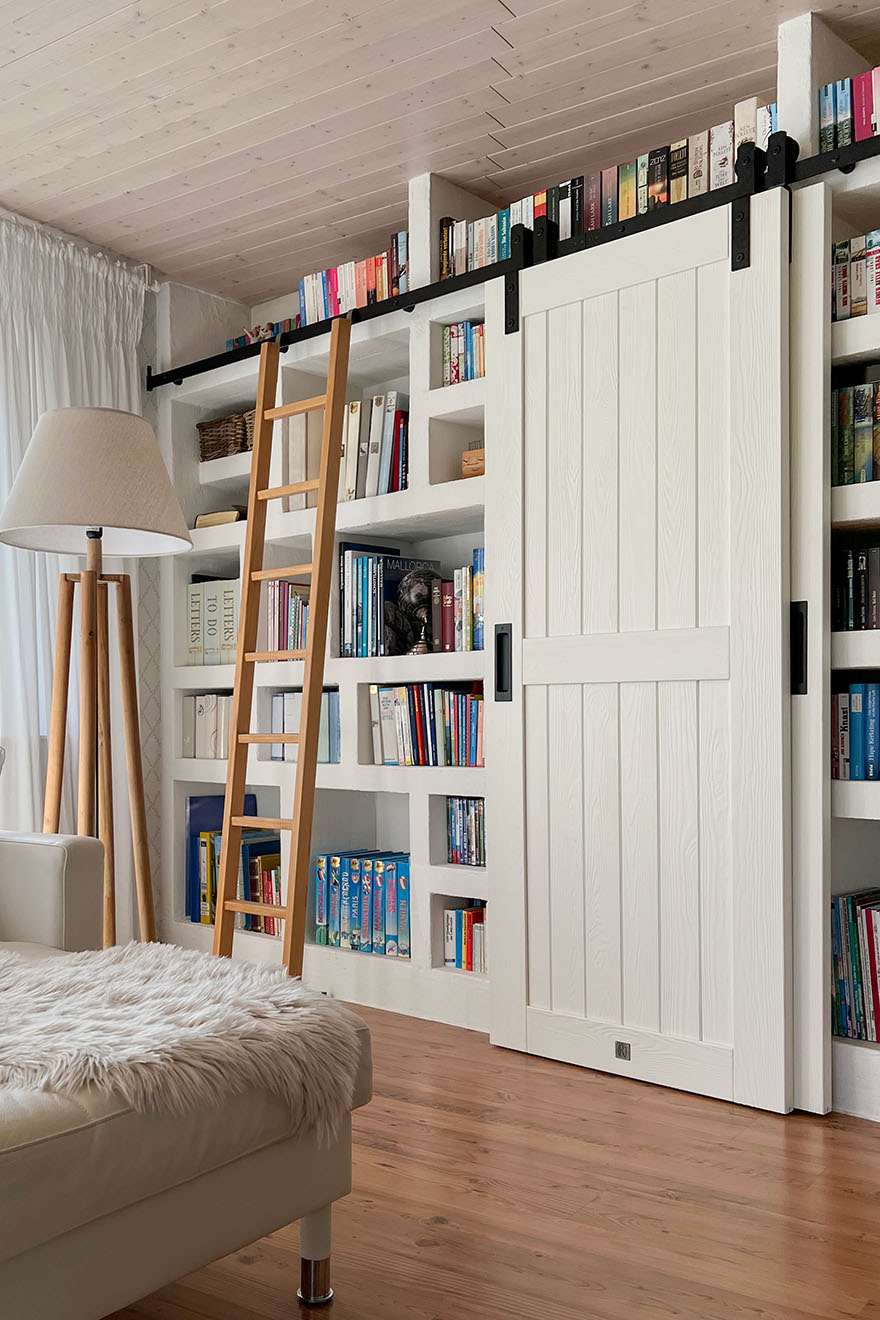 eine Leiter und eine weiße Schiebetür in der Anordnung einer Heimbibliothek im Wohnzimmer