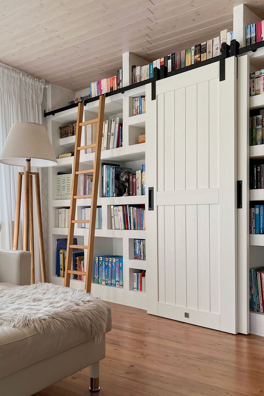 eine Leiter und eine weiße Schiebetür in der Anordnung einer Heimbibliothek im Wohnzimmer
