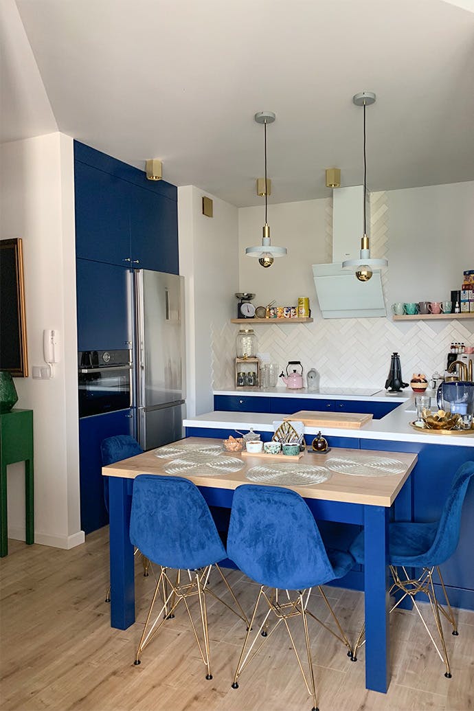 chaises bleues et accessoires dorés dans la cuisine ouverte