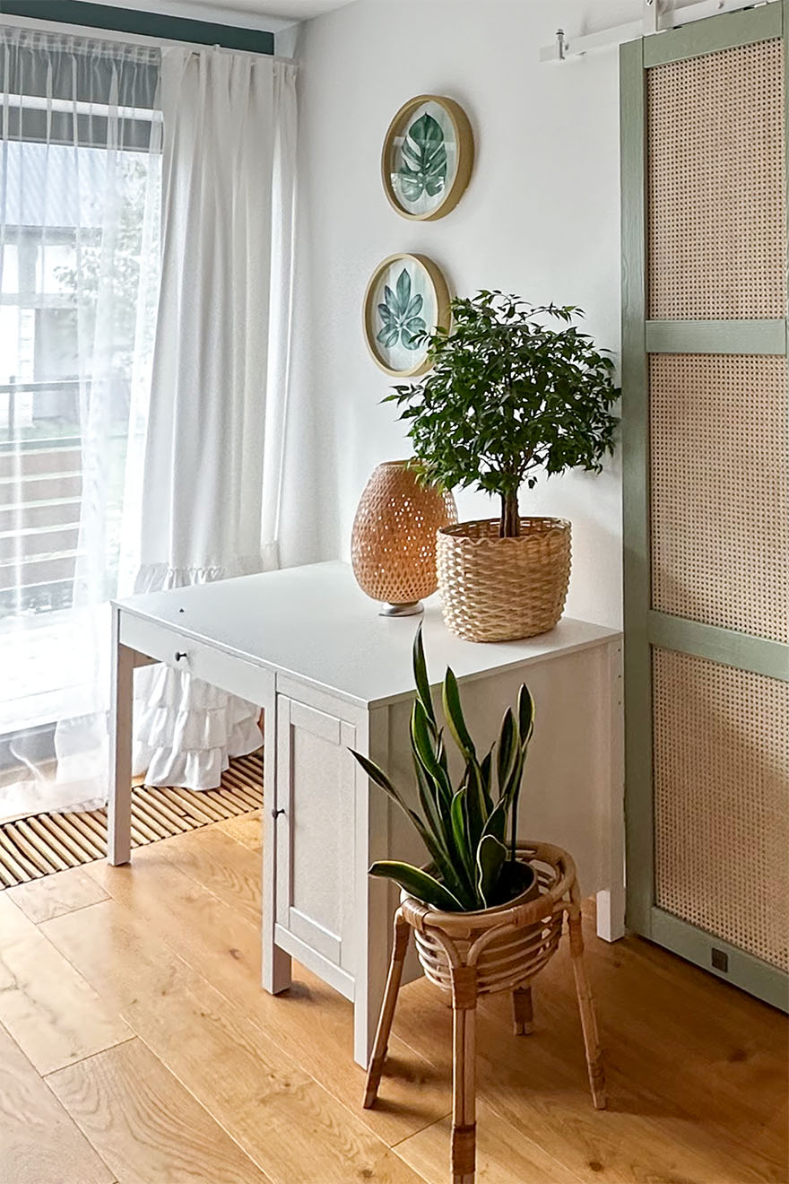 Pflanzen in dekorativen Töpfen und ein weißer Schminktisch neben einem großen Fenster