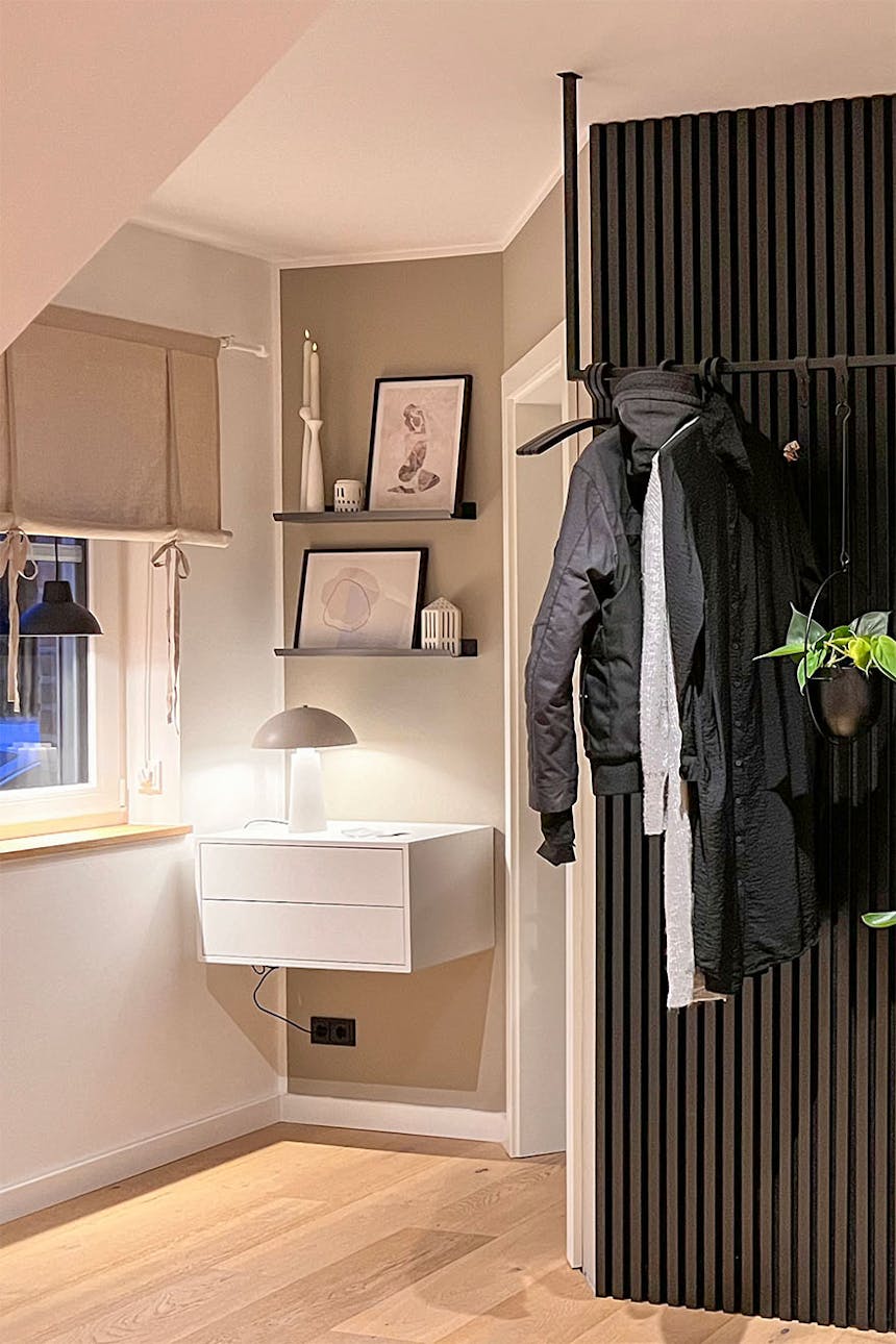 schwarze Lamellen an der Wand und ein weißer Tisch im Flur