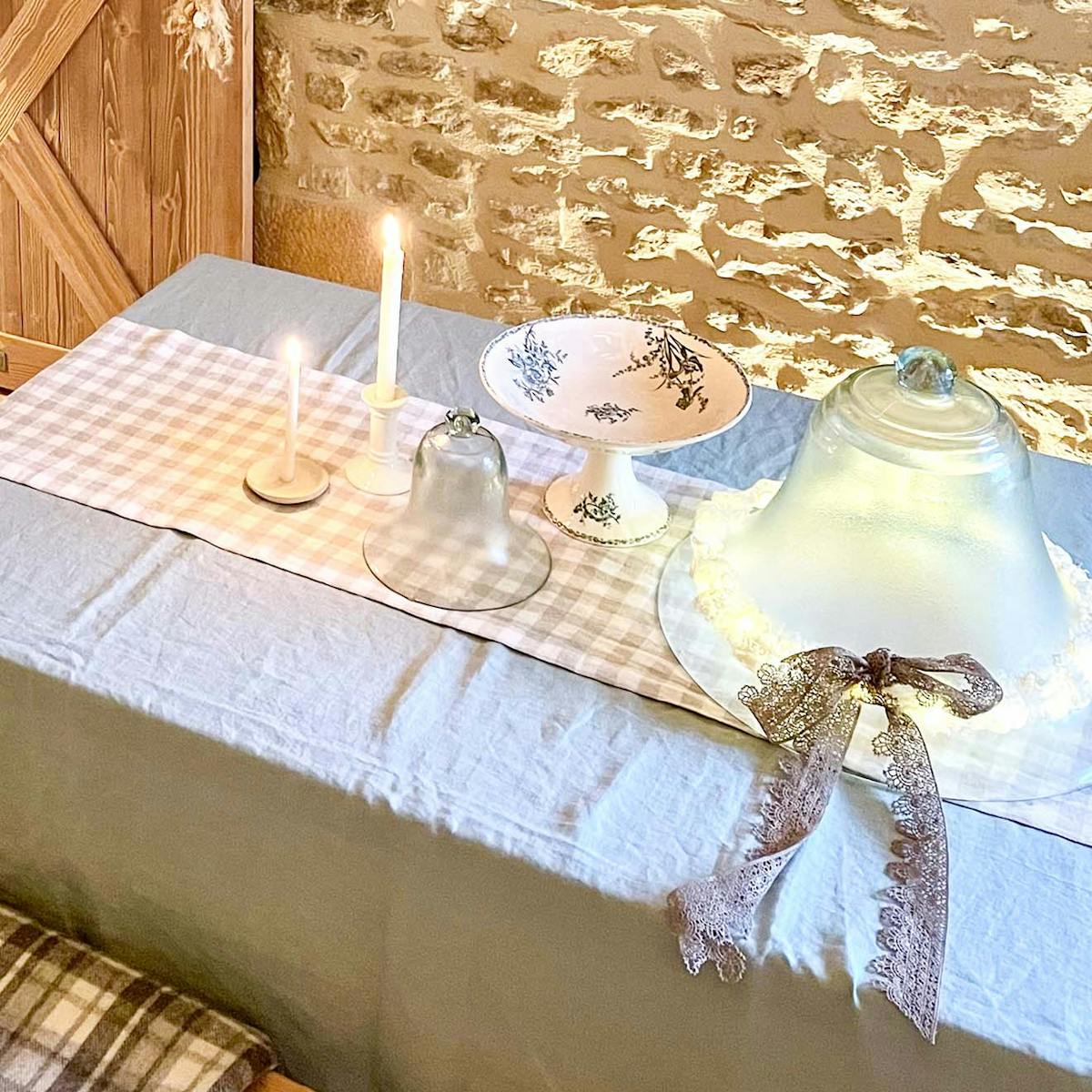 szklane i porcelanowe naczynia na stole przykrytym lnianym niebieskim obrusem