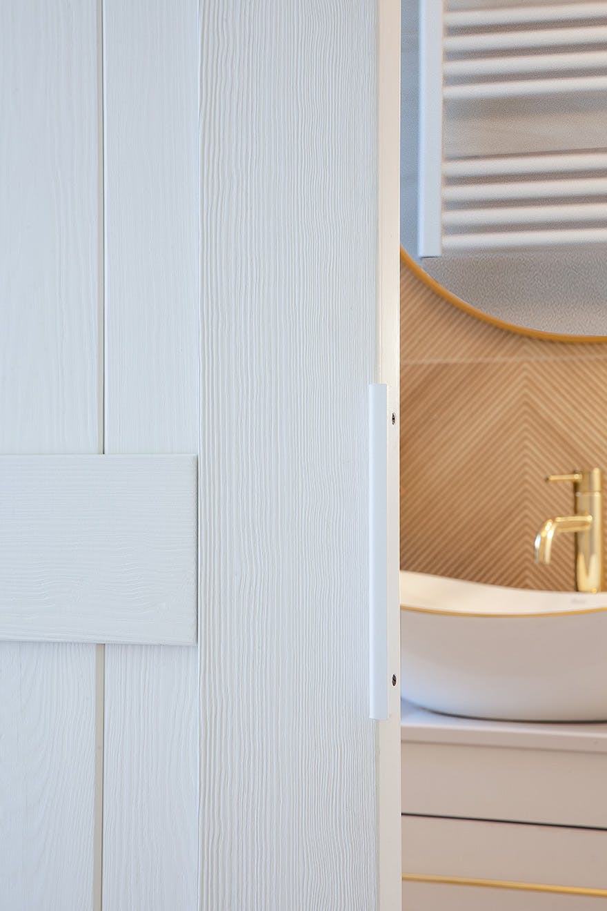 a half-open white wooden door revealing a fragment of the bathroom