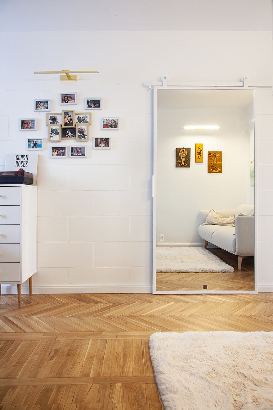 photo gallery in wooden frames next to a metal white door with a mirror