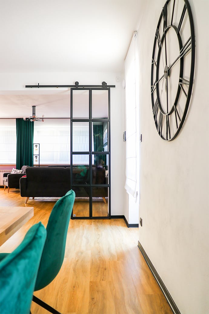 horloge murale métal noir, horloge style industriel, déco loft, porte métal avec vitre, porte loft, porte coulissante verre métal, porte verre cadre noir, chaises de salle à manger vertes, salon ouvert sur salle à manger, rideaux verts