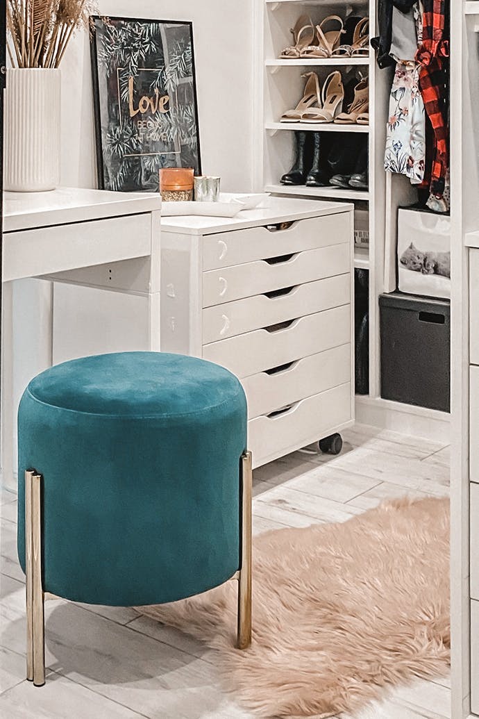 Une coiffeuse blanche et un siège turquoise dans un dressing aux couleurs vives