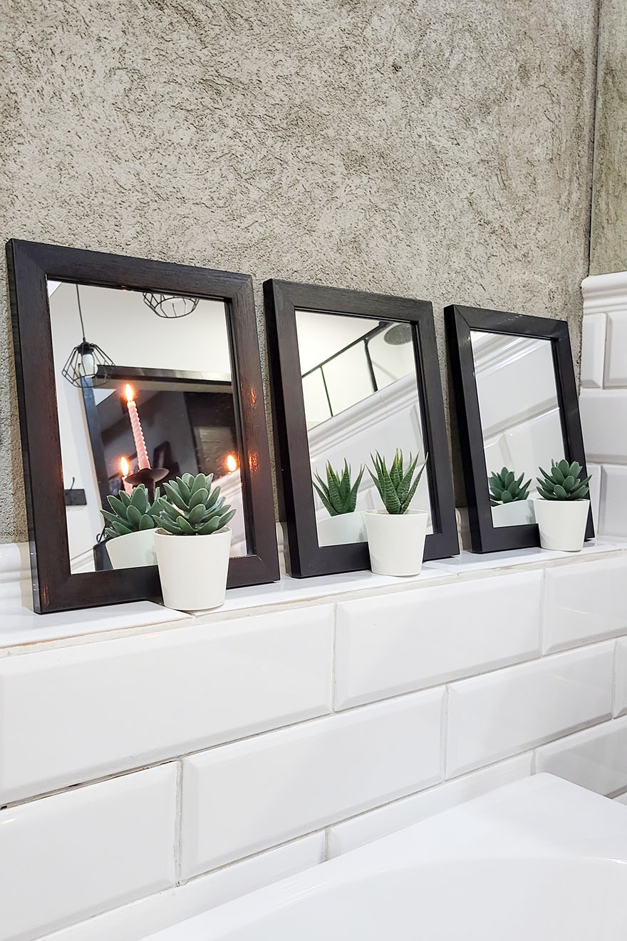 ein Satz kleiner Spiegel mit quadratischem Rahmen über der Badewanne im Badezimmer