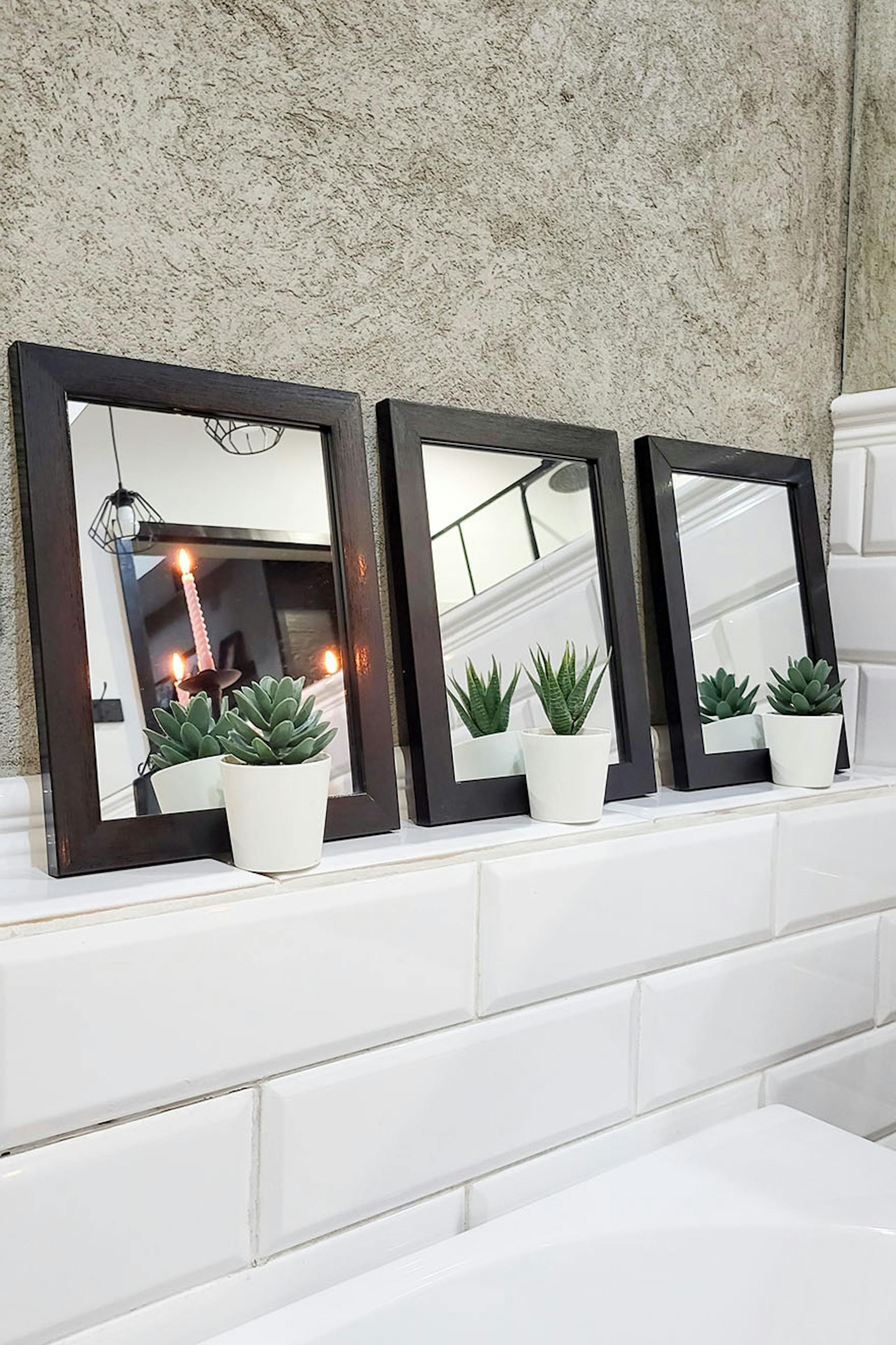 ein Satz kleiner Spiegel mit quadratischem Rahmen über der Badewanne im Badezimmer