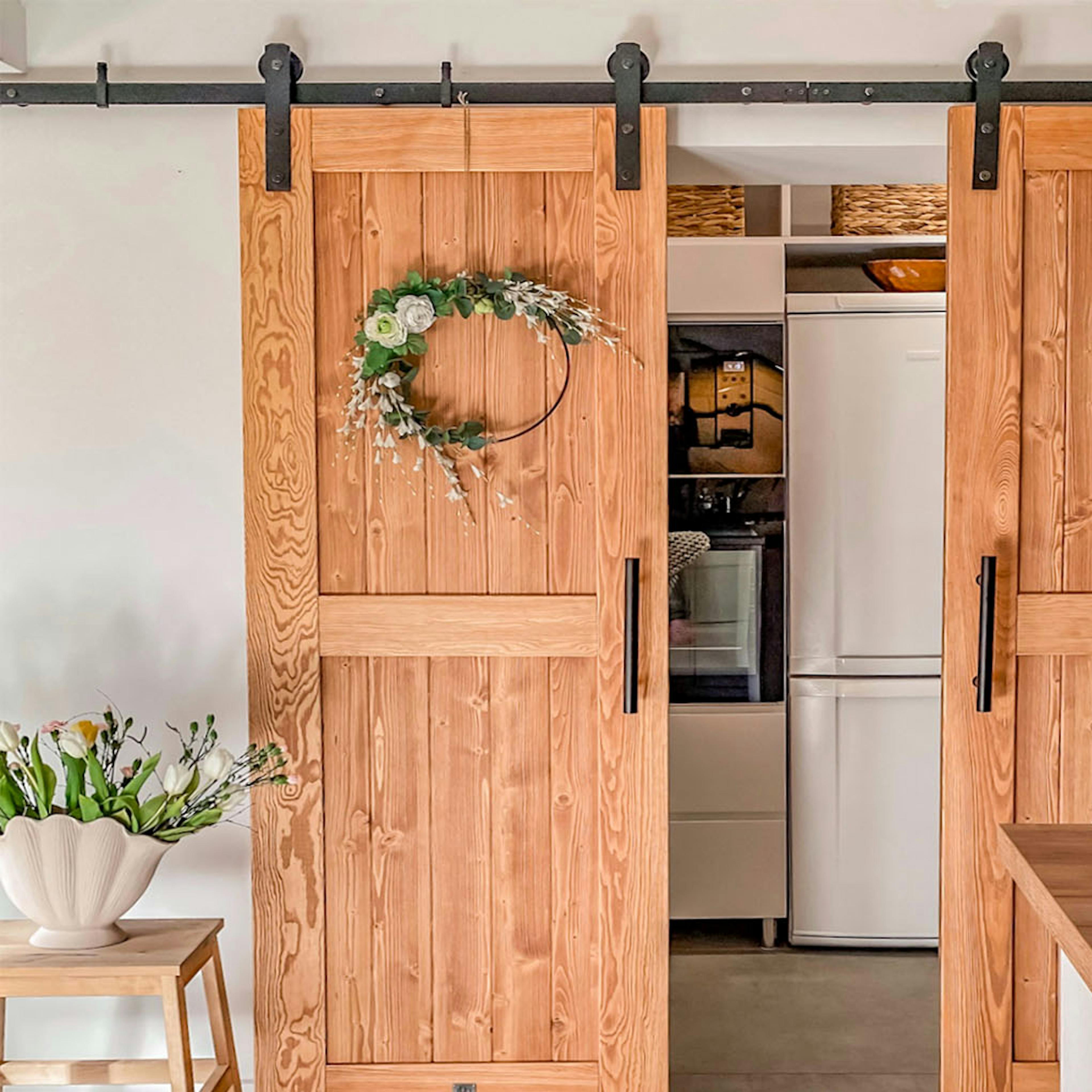 appareils électroménagers cachés dans un renfoncement de cuisine fermé par des doubles portes coulissantes