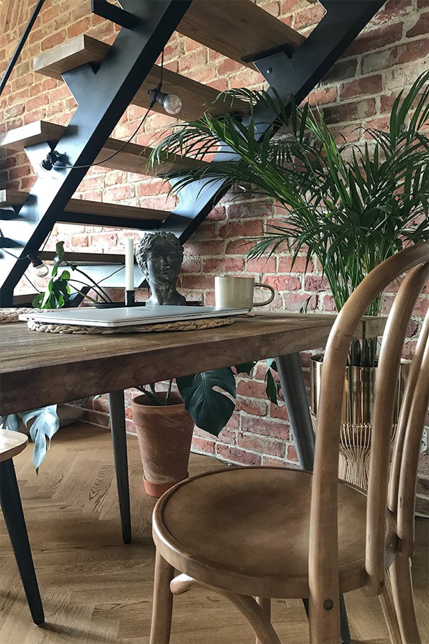 Retro-Stühle, Metalltreppen im Loft-Stil, Loft-Interieur, Ziegel an der Wand, Lofts-Stil, Vintage-Accessoires, große Pflanzen im Wohnzimmer, Metalllampen