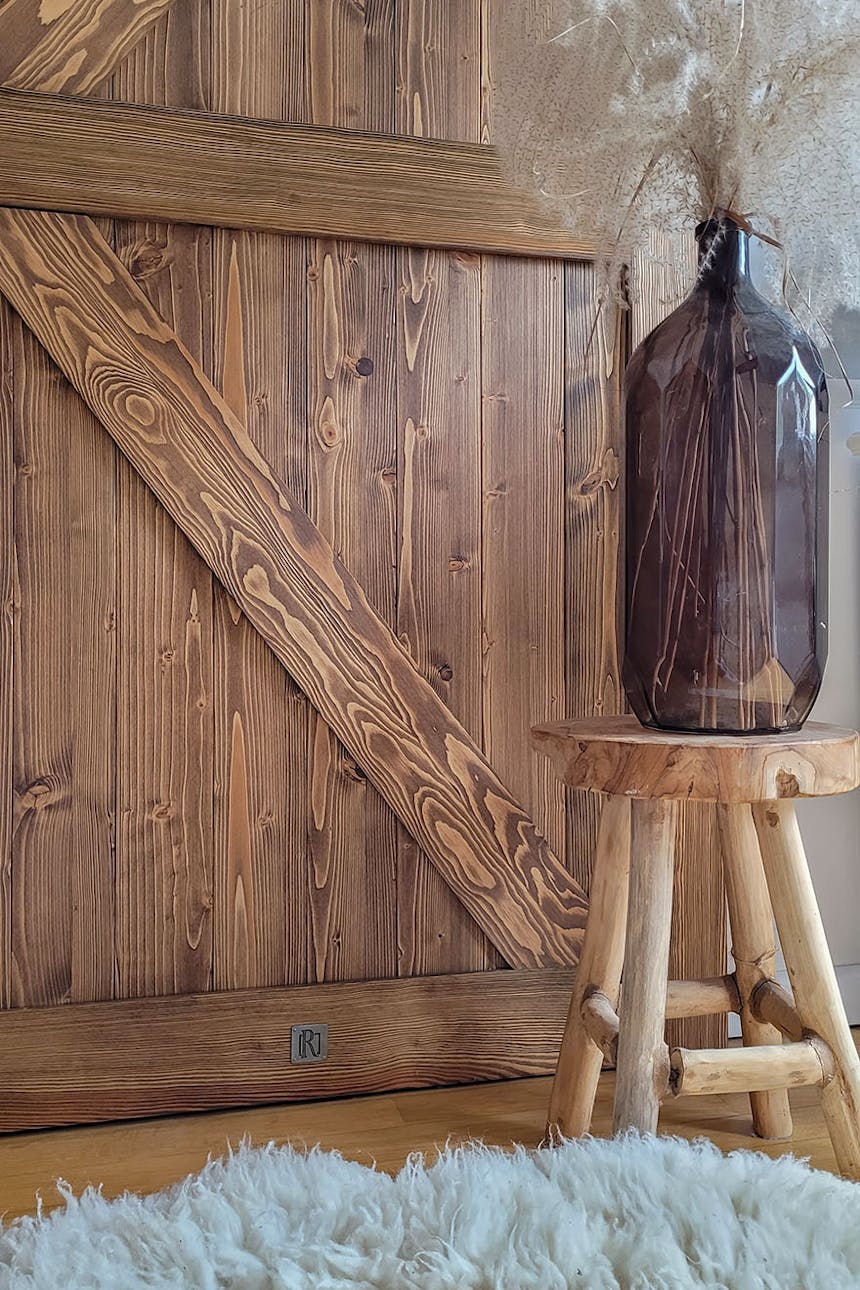 Vase auf einem Holzhocker neben einer Massivholztür