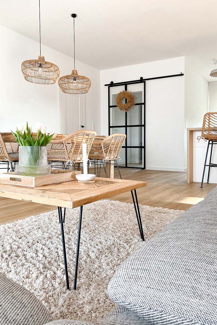 kwadratowy stolik kawowy z naturalnego drewna na metalowych nogach w salonie połączonym z jadalnią