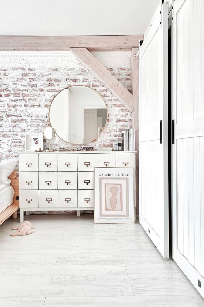 un miroir rond au-dessus d'une commode rustique à côté d'une porte coulissante en bois blanc