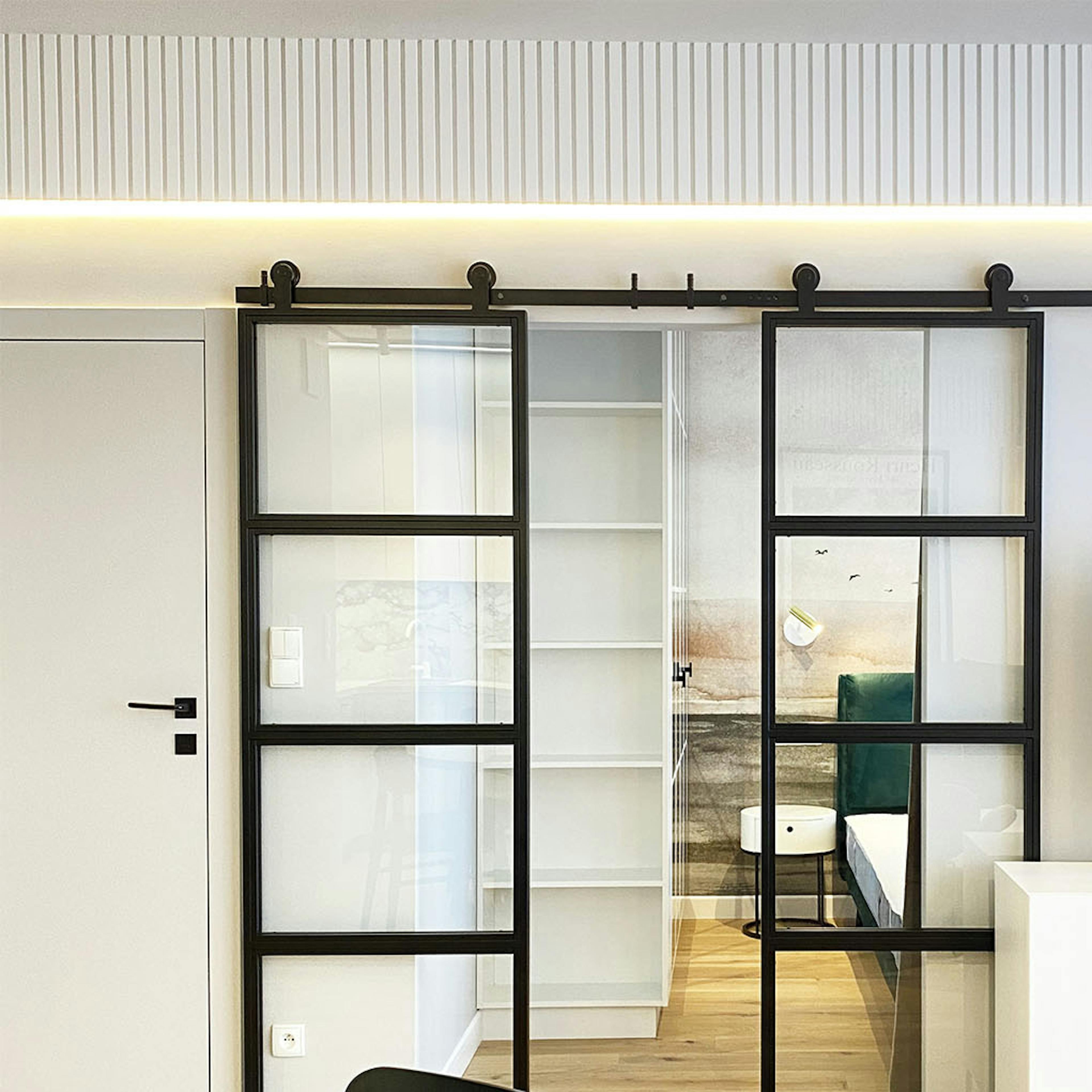portes coulissantes en double vitrage dans un cadre métallique séparant le salon de la chambre dans un appartement moderne