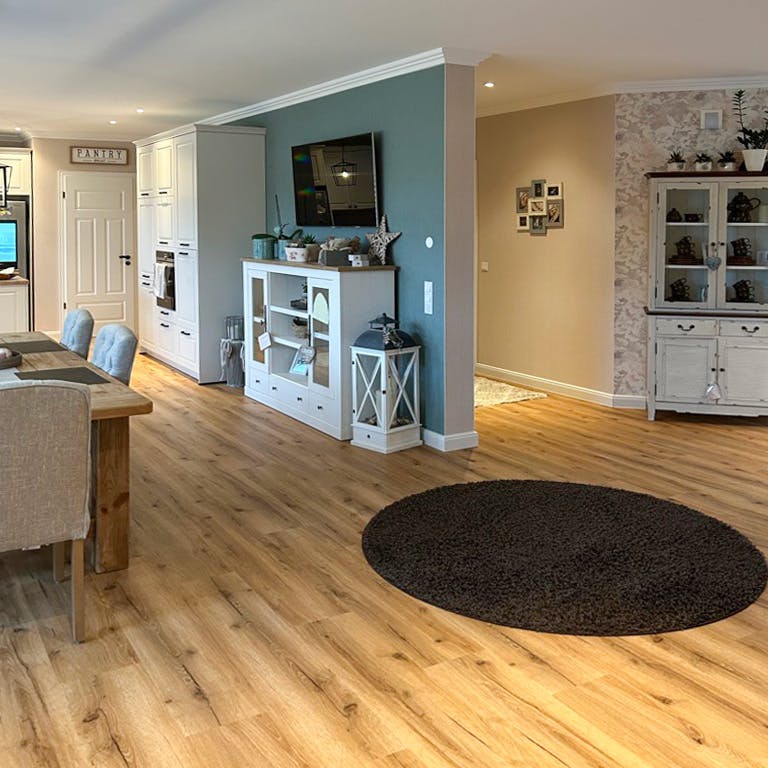wooden floor and white furniture in an open kitchen with a dining area