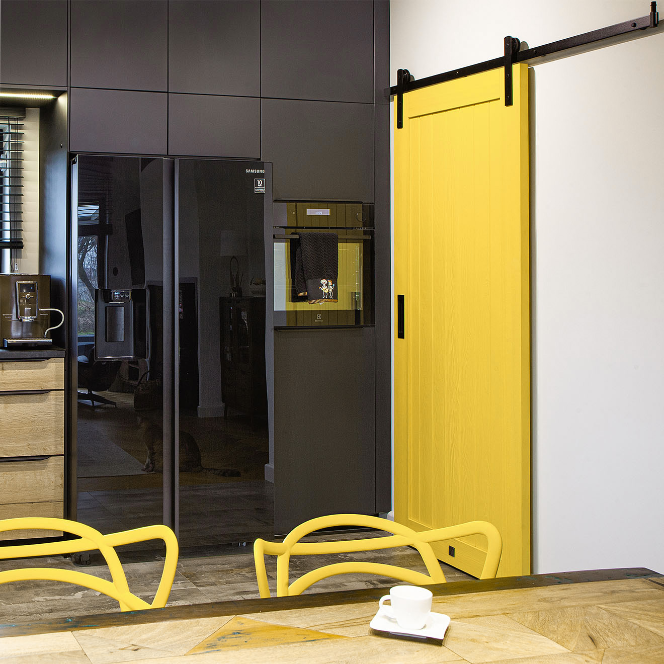 gelbe Schiebetür zur Speisekammer mit schwarzen Schränken