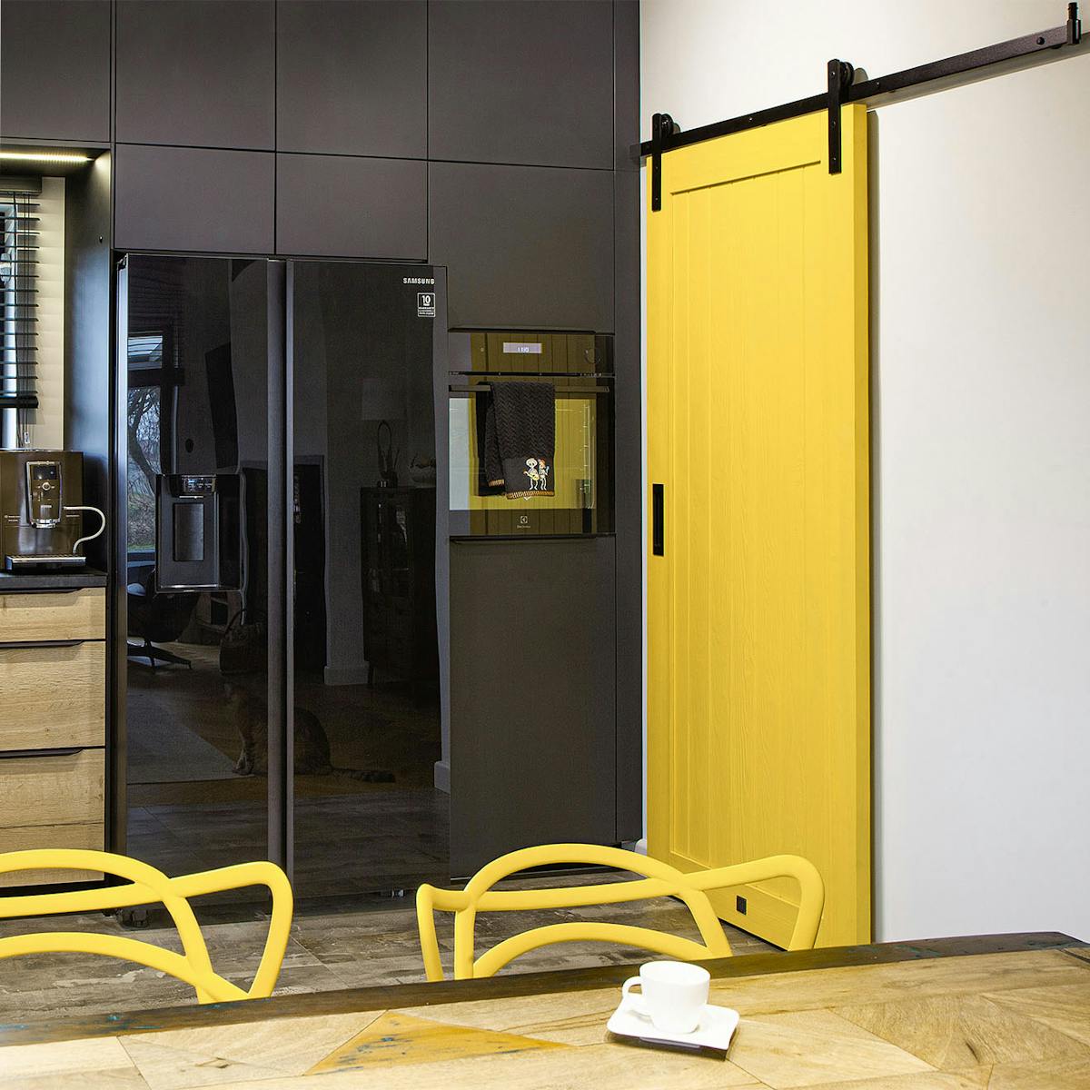 gelbe Schiebetür zur Speisekammer mit schwarzen Schränken