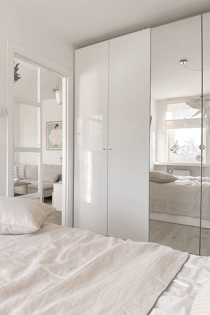 biała szafa z lustrem w jasnej sypialni