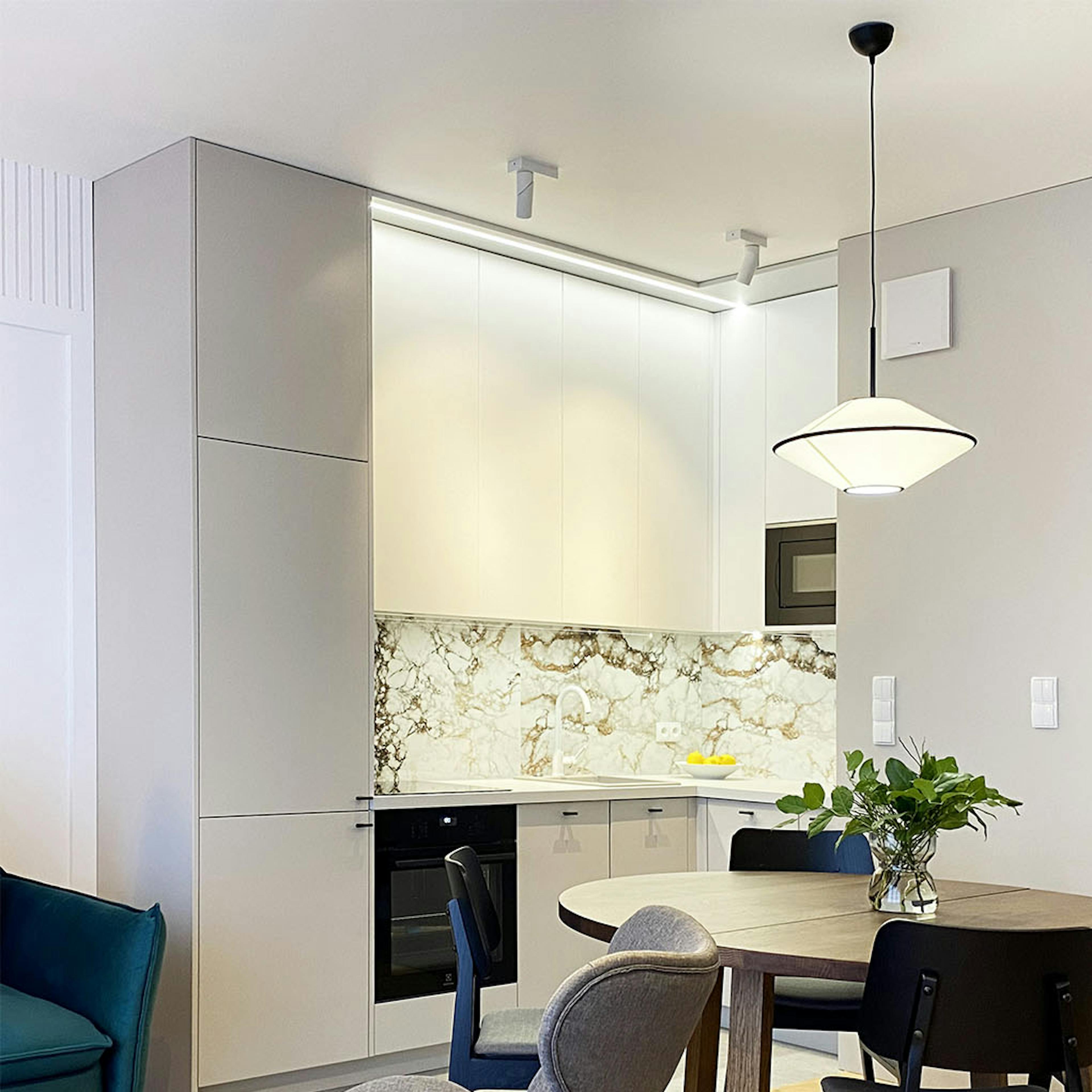 table à manger de couleur noyer, chaises noires sur fond de cuisine lumineuse dans un appartement moderne