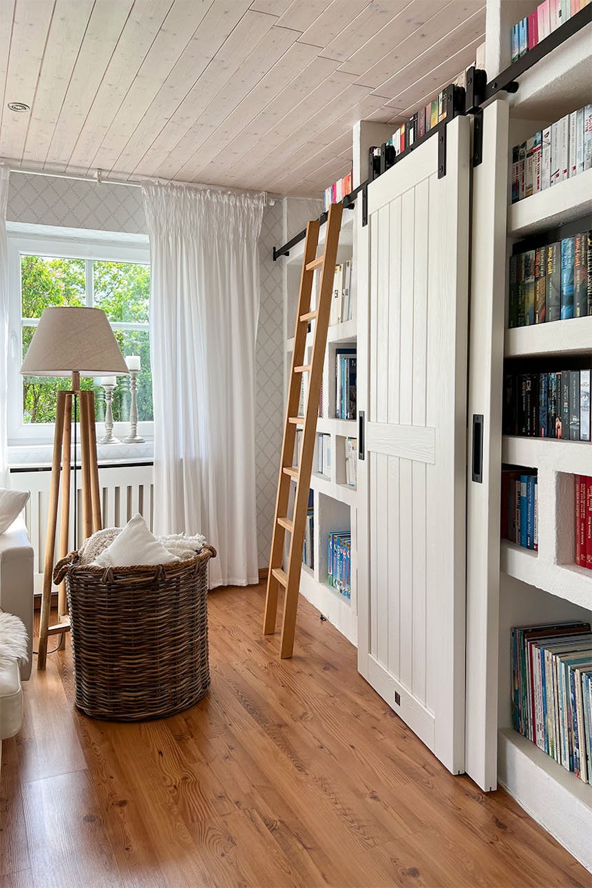Leiter und weiße Schiebetür in der Anordnung der Bibliothek im Wohnzimmer