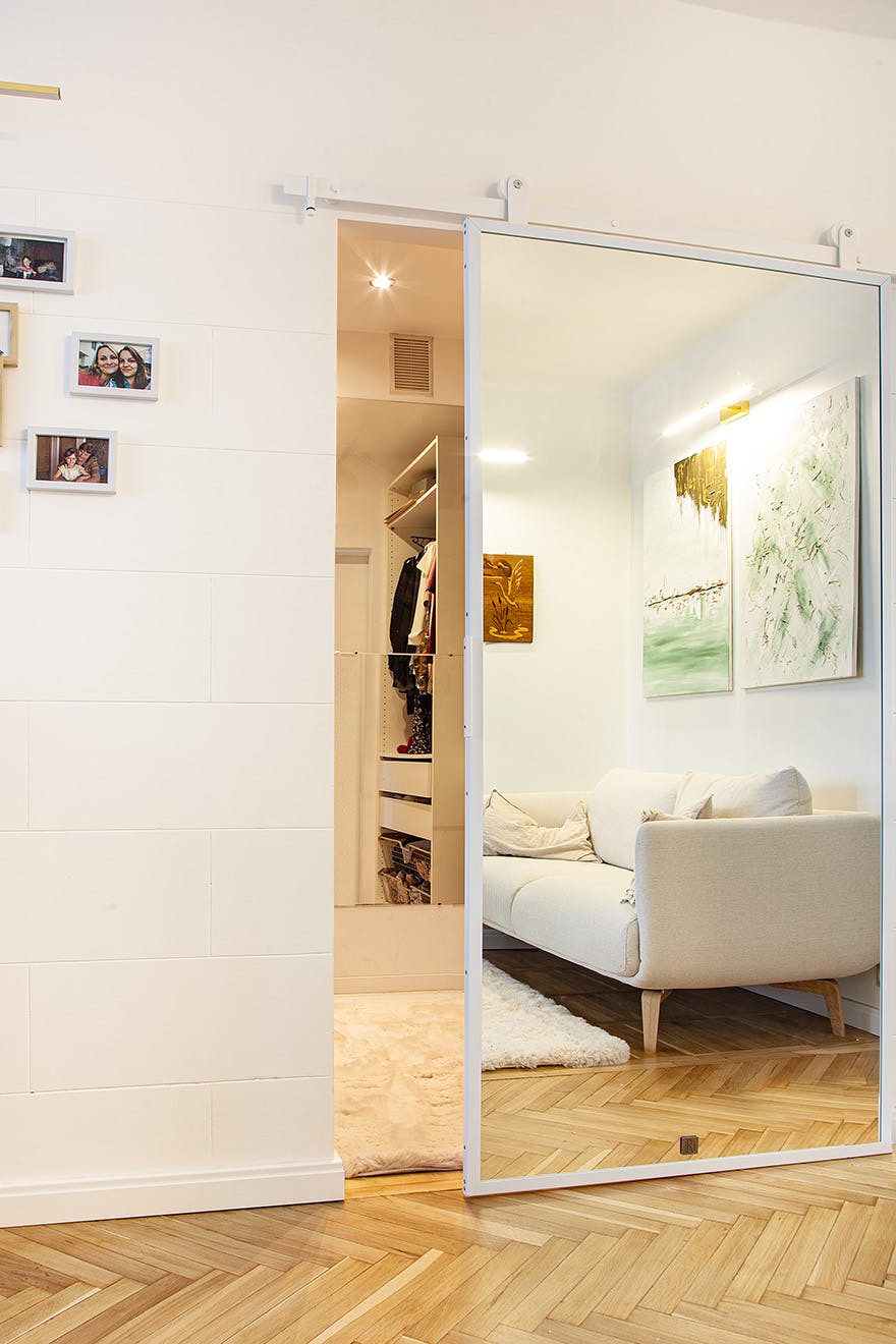 a wardrobe behind a white sliding door with a mirror in a white metal frame