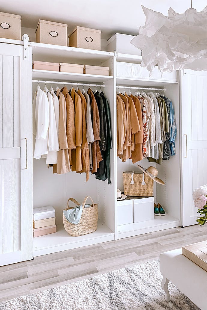 Armoire blanche et grande avec des vêtements dans un dressing pour femme