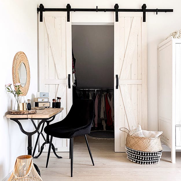 une coiffeuse rustique, une chaise noire et une porte coulissante étroite dans la chambre avec une petite armoire