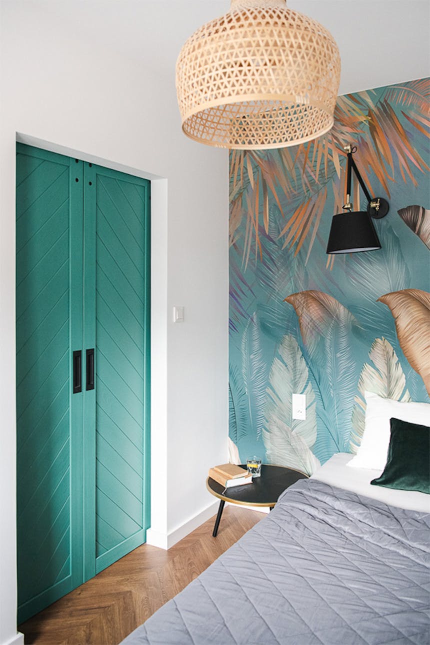 sypialnia z turkusowymi drzwiami dwuskrzydłowymi i dekoracyjną tapetą