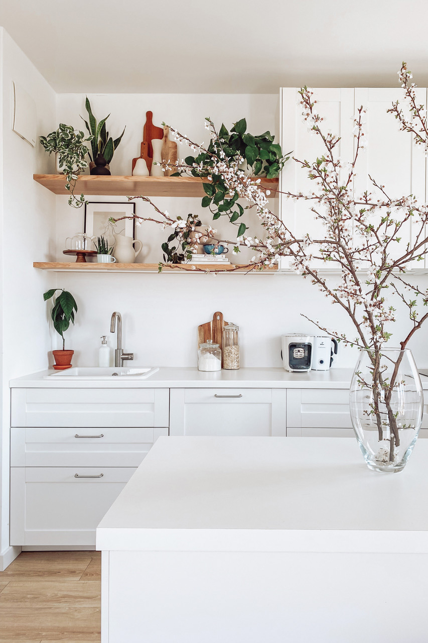 große weiße schränke in der küche, weiße kücheninsel, blumen und dekorationen in der weißen küche