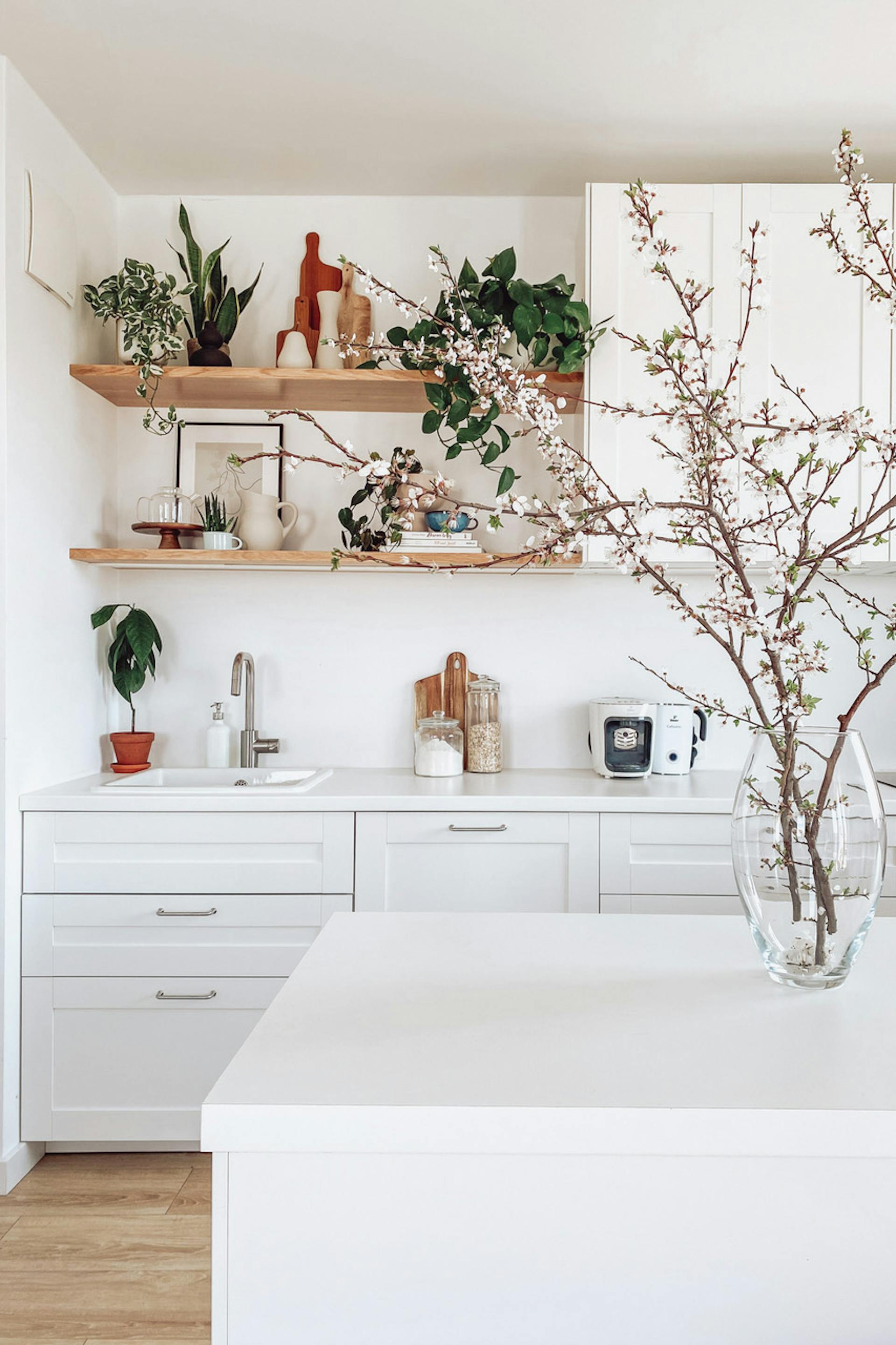 große weiße schränke in der küche, weiße kücheninsel, blumen und dekorationen in der weißen küche