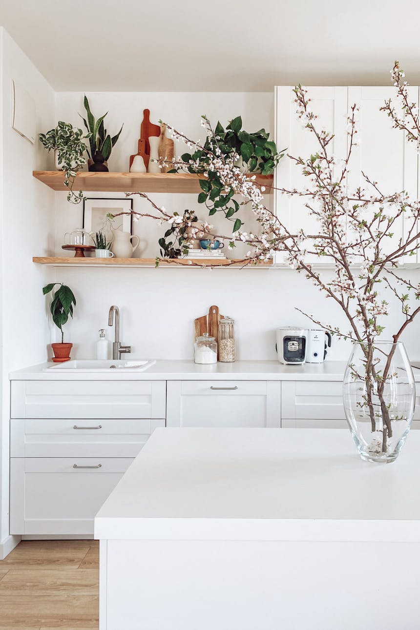 große weiße schränke in der küche, weiße kücheninsel, blumen und dekorationen in der weißen küche