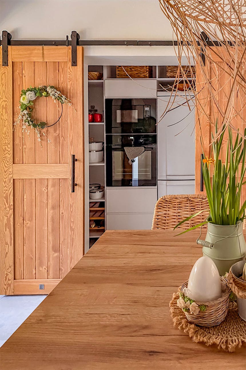 drewniane drzwi przesuwne zamykające wnękę w kuchni z urządzeniami AGD