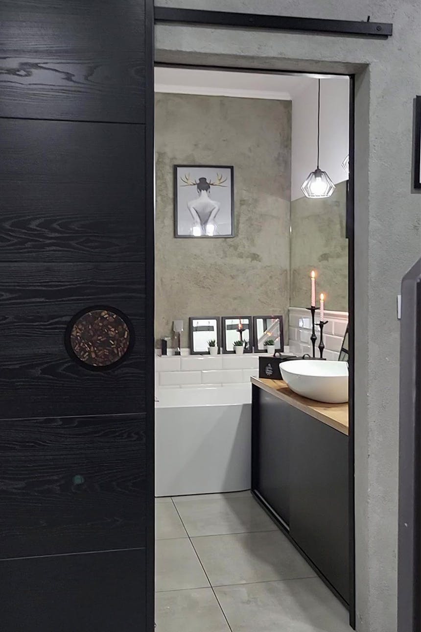 Eine angelehnte Schiebetür zeigt das Innere eines weiß-grauen Badezimmers