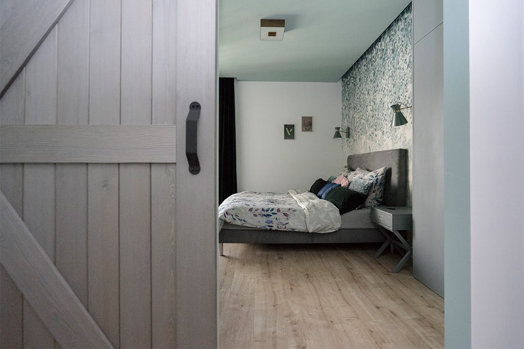 porte coulissante ouverte sur la chambre avec un grand lit et un papier peint décoratif