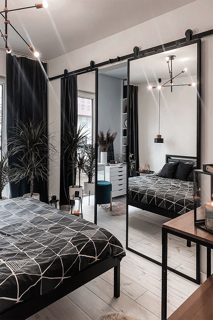 Une double porte coulissante ouverte avec un miroir montrant un fragment d'une armoire avec une coiffeuse blanche