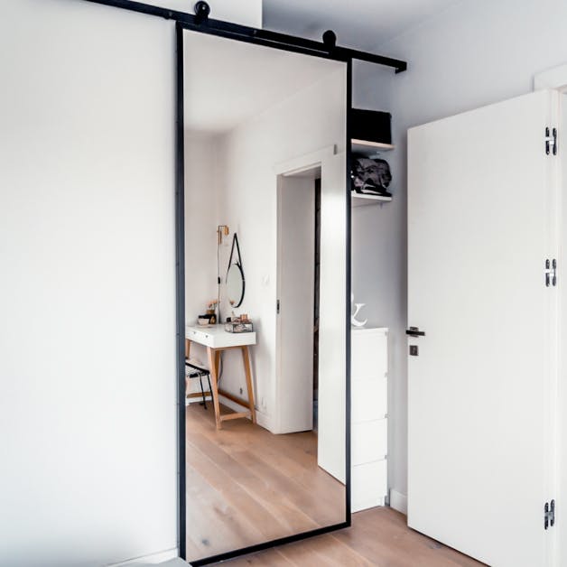 porte coulissante avec un miroir dans un cadre en métal noir fermant le renfoncement dans la chambre