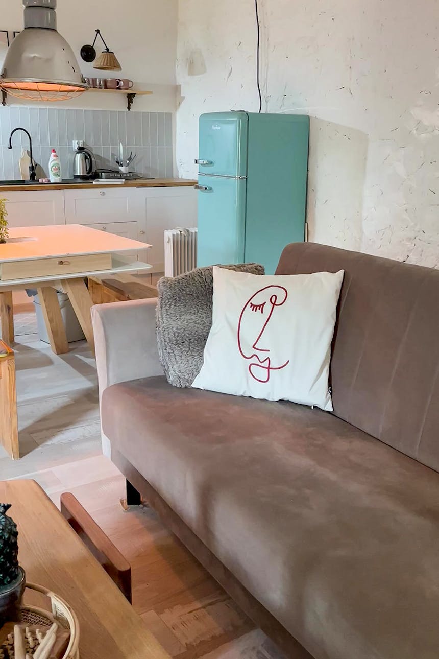 Ein braunes Sofa im Wohnzimmer und ein blauer Kühlschrank in der Küche im Landhausstil